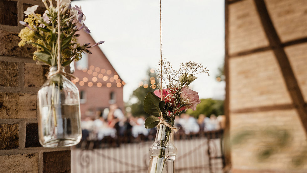 individuelle Hochzeitsdekoration: Blumen in kleinen Vasen, die von Bogengang des Kultourhof Raestrups hängen
