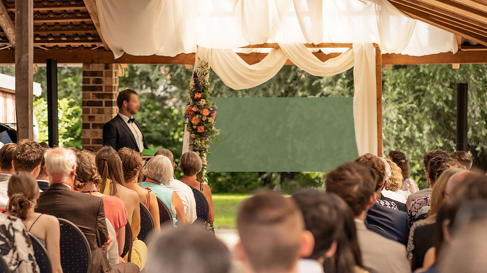 Hochzeitsgesellschaft sitzt vor einem Traubogen im Bogengang vom Kultourhof Raestrup und wartet auf das Hochzeitspaar