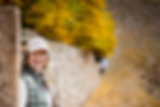 Die FASTENSEELE Gründerin Kerstin Rogowski steht vor einer Mauer mit herbstlichen Bäumen im Hintergrund und lächelt