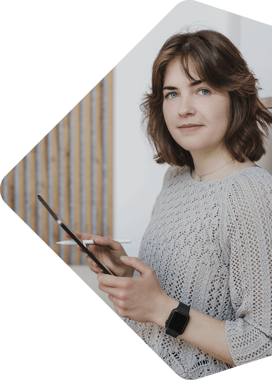 Bild von Elisa Deitert, steht mit einem Tablet in der Hand und schaut in die Kamera