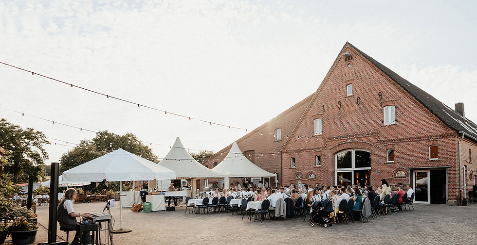 Der Innenhof vom Kultourhof Raestrup mit dem Haupthaus im Hintergrund. Im Hof stehen Catering Zelte, Tische, Stühle und Gäste