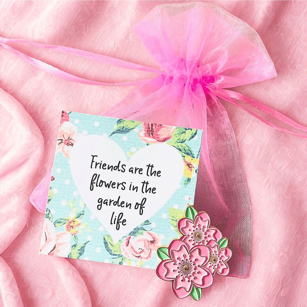 Pink flowers pin badge on a pink organza gift bag and with a message tag that reads Friends are the flowers in the garden of life