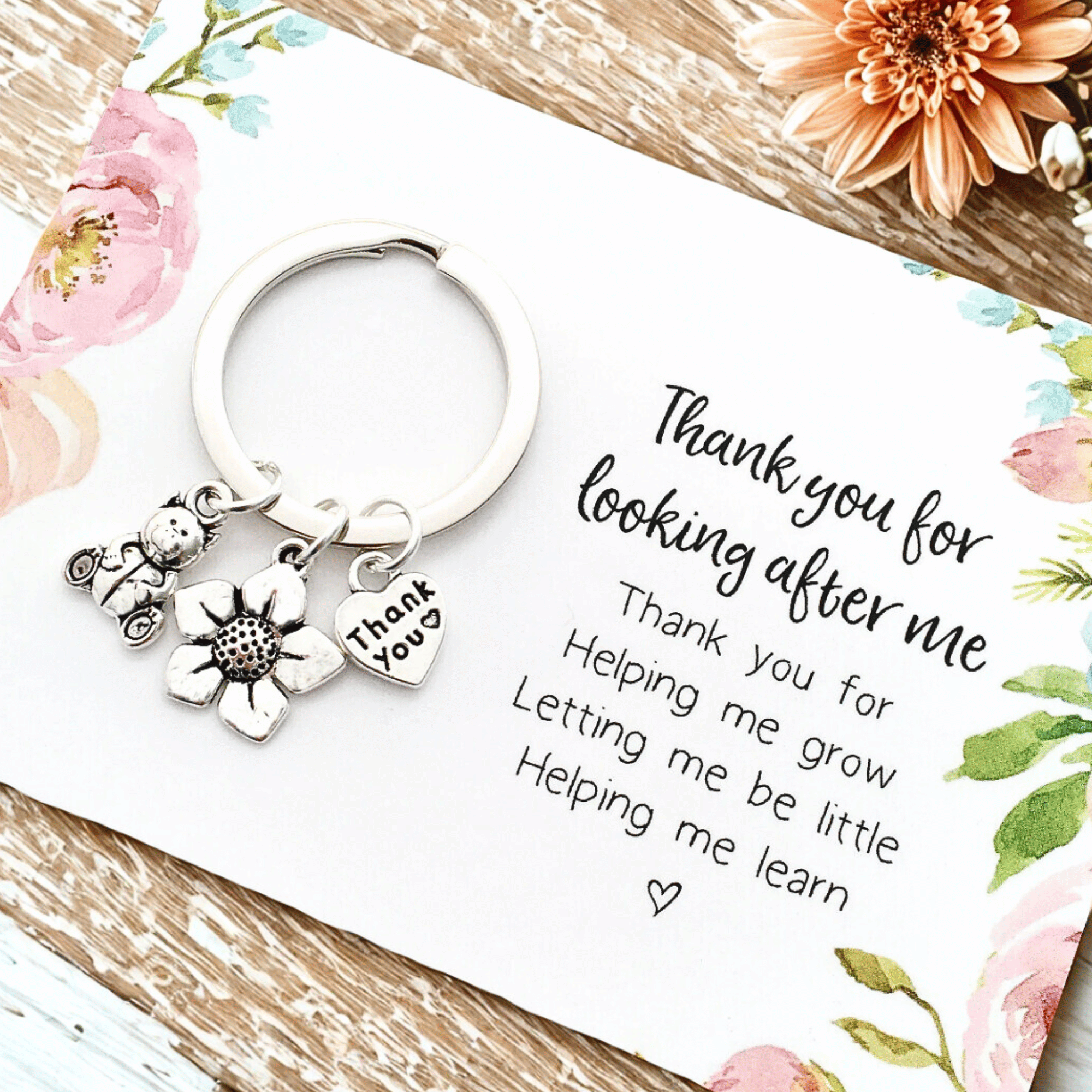 Charm keyring with a teddy bear charm, a flower charm and a thank you charm on a flat card which reads "Thank you for looking after me" 