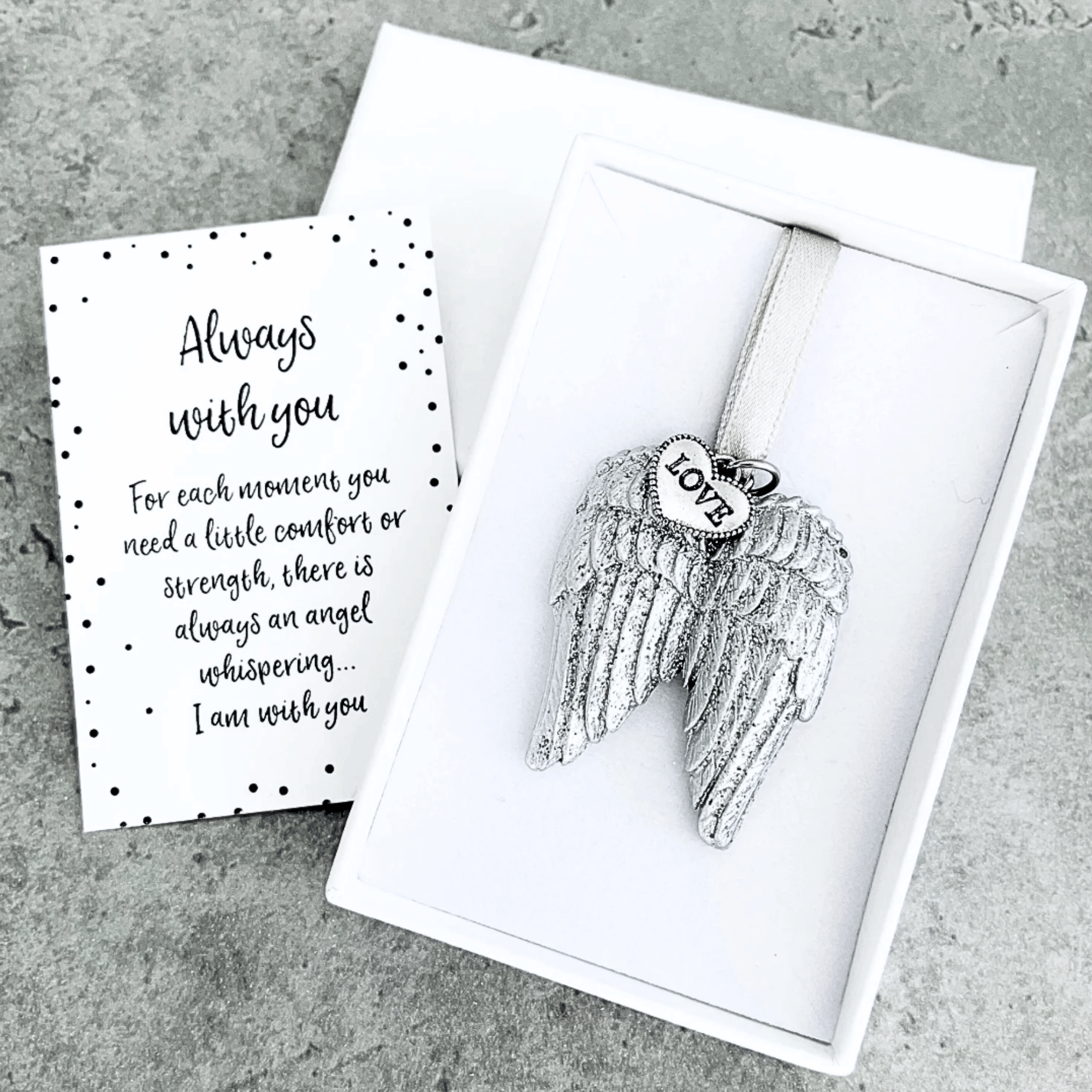 Silver glitter angel wings with a love heart charm and ribbon hanger presented in a white gift box with a message card 