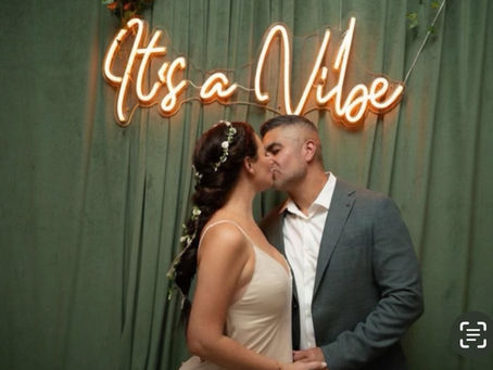 A couple kissing under the "It's a Vibe" sign.