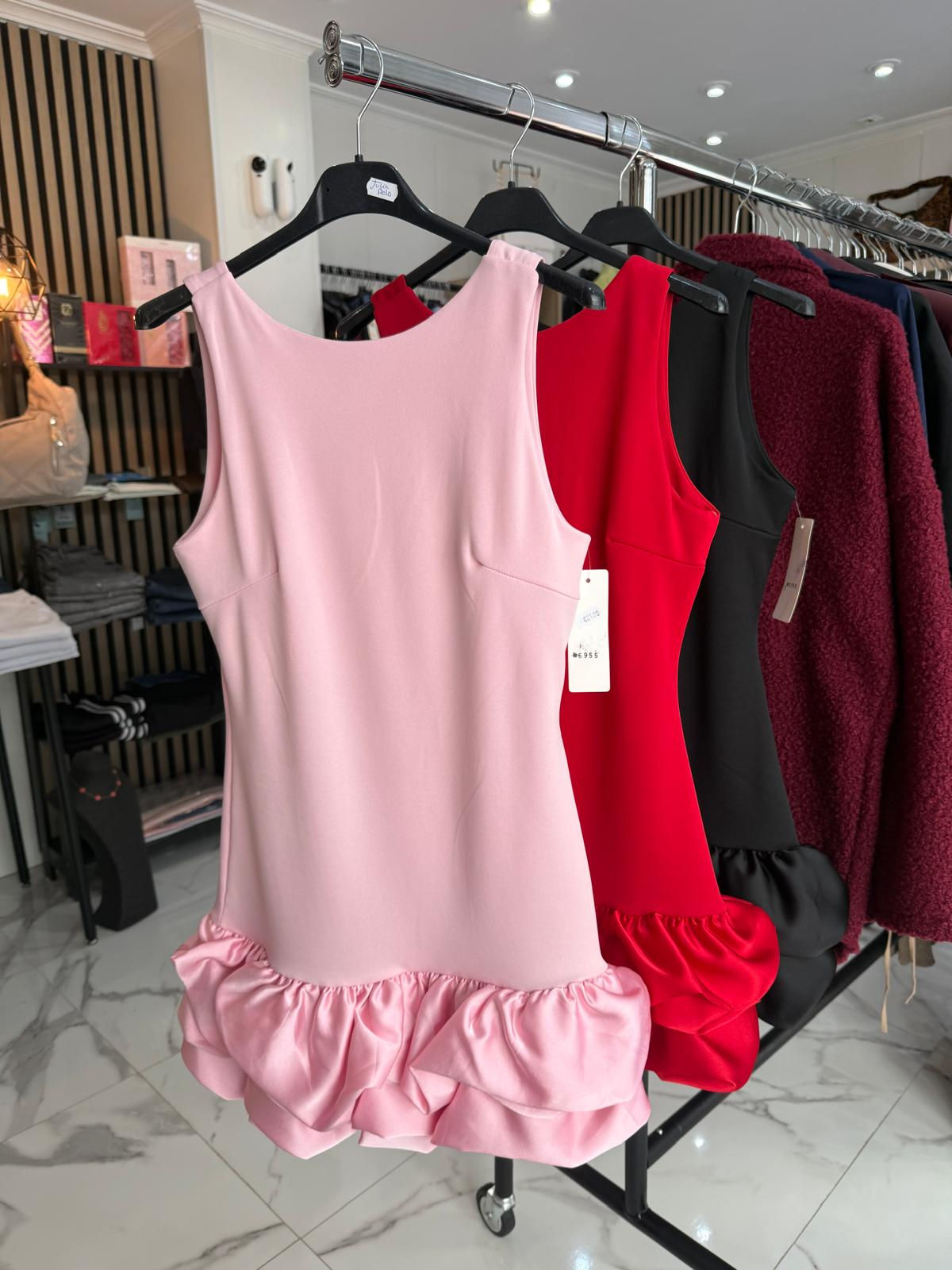 Vestidos rosa, rojo y negro con volantes en perchas