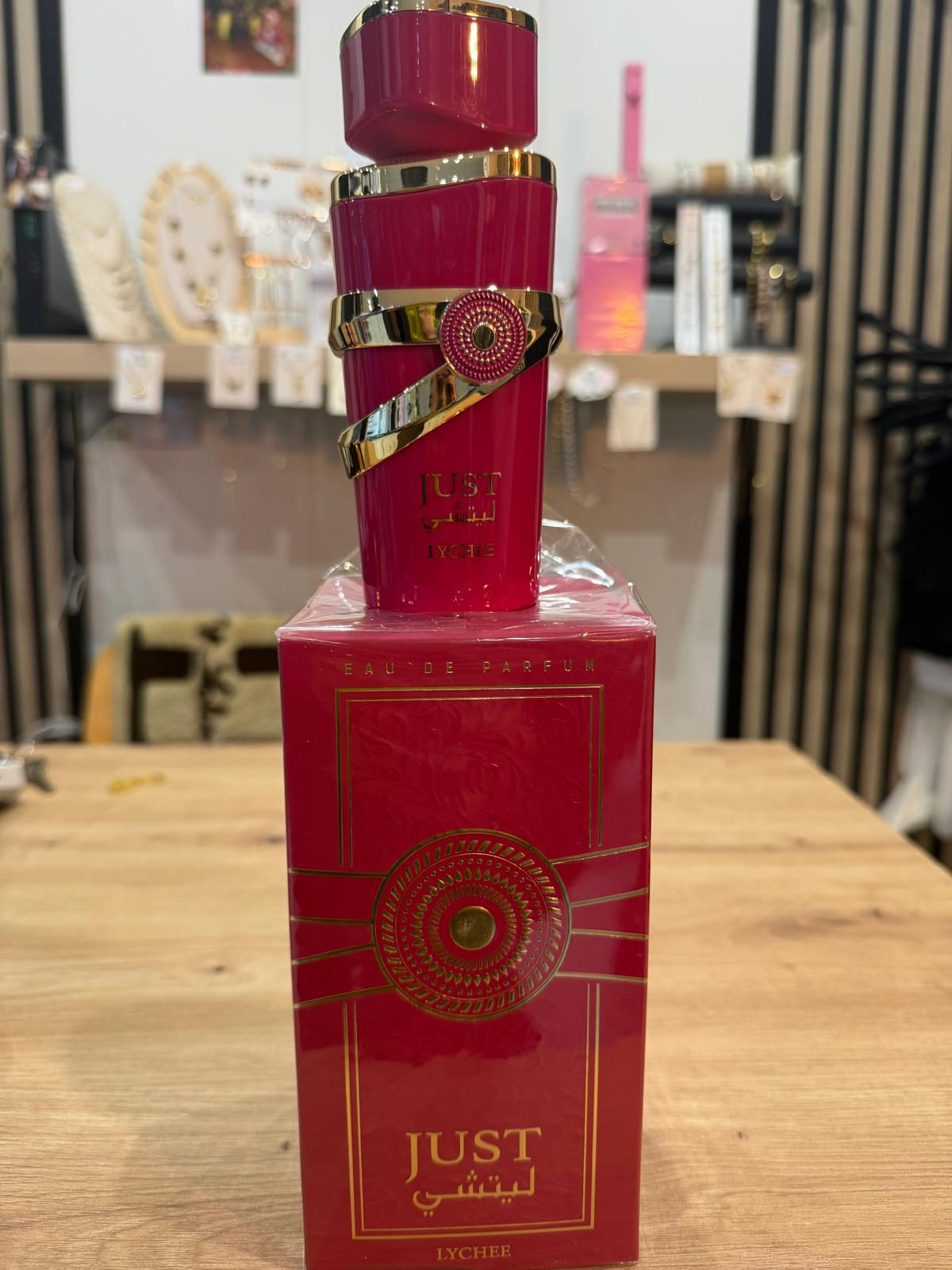 Botella de perfume rosa con su caja y detalles dorados