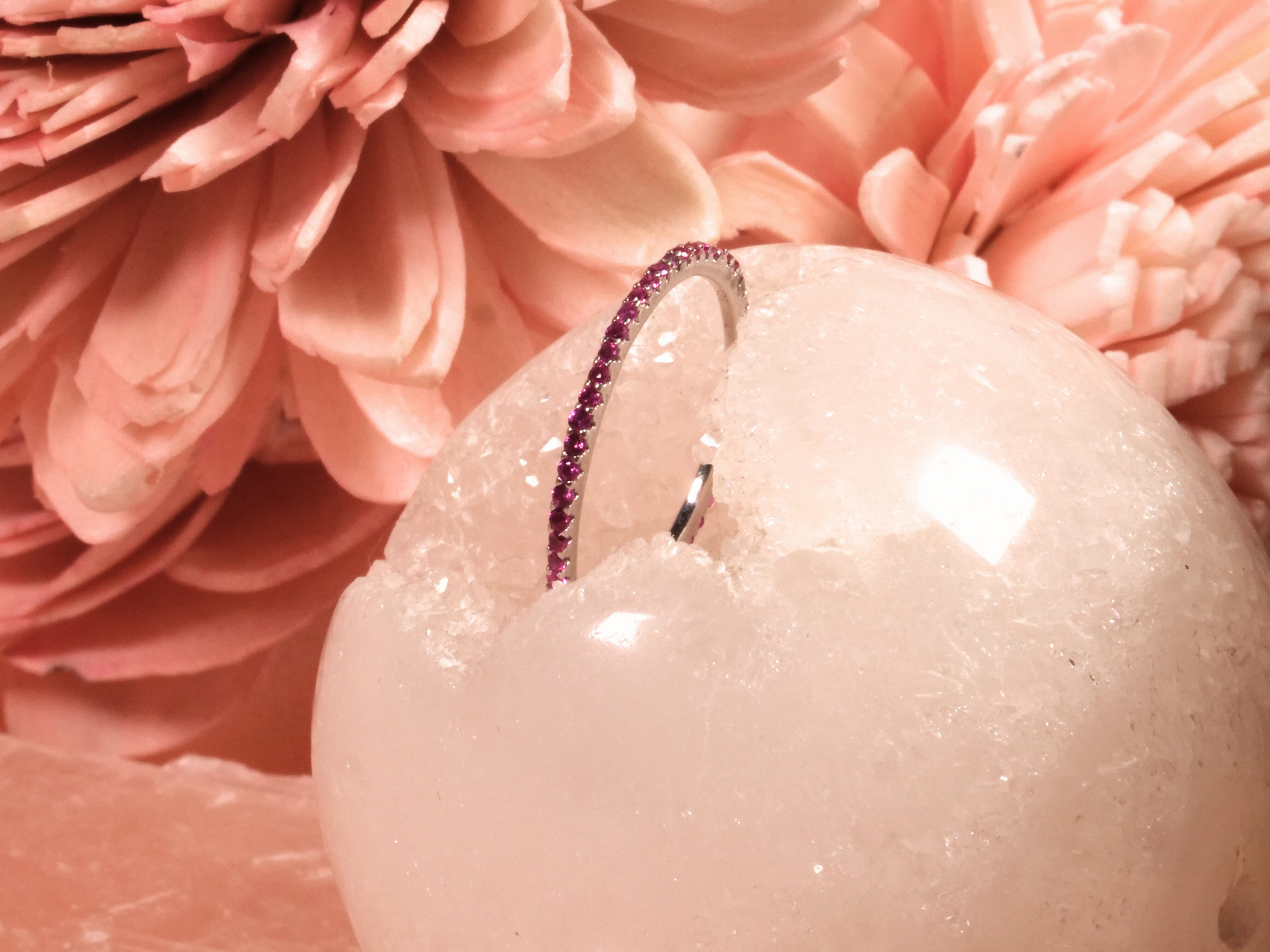 ring is a slender silver band designed with a pavé setting of round pink gemstones.