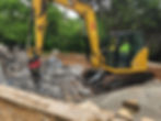 An excavator demolishing a pool floor
