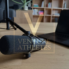 Microphone and laptop on table with Venture Athletes logo, home office setup