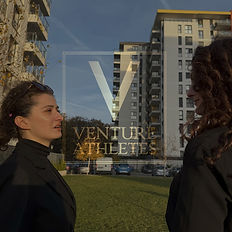 Two women looking at buildings with Venture Athletes logo, outdoors Venture Athletes