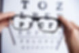 A picture of a person holding glasses over an eye test