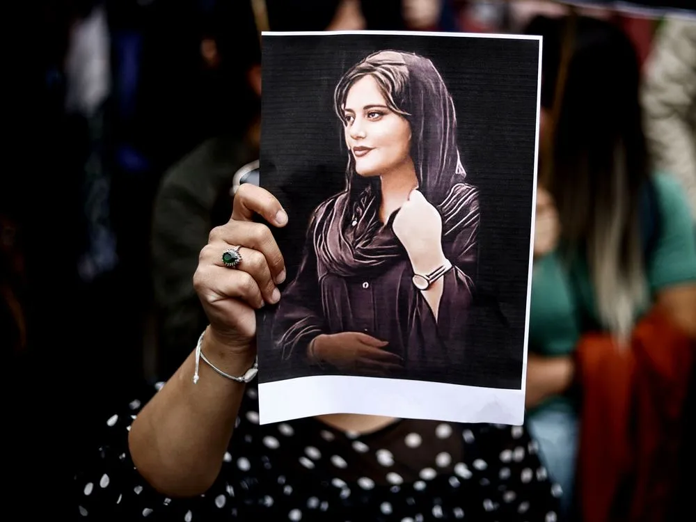 A woman holding a picture of Mahsa Amini.