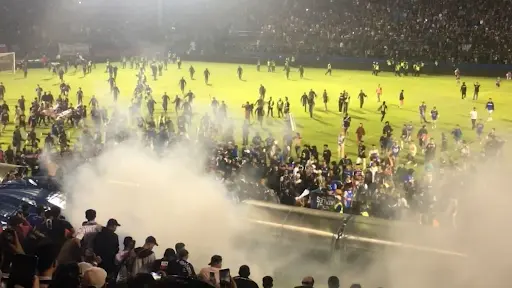 The release of tear gas with fans climbing barriers to escape