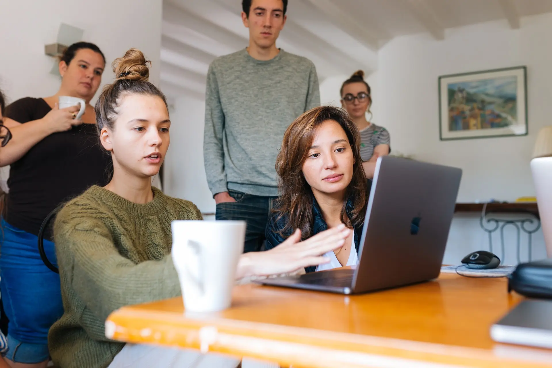 A woman explaining something from a laptop to a group of people