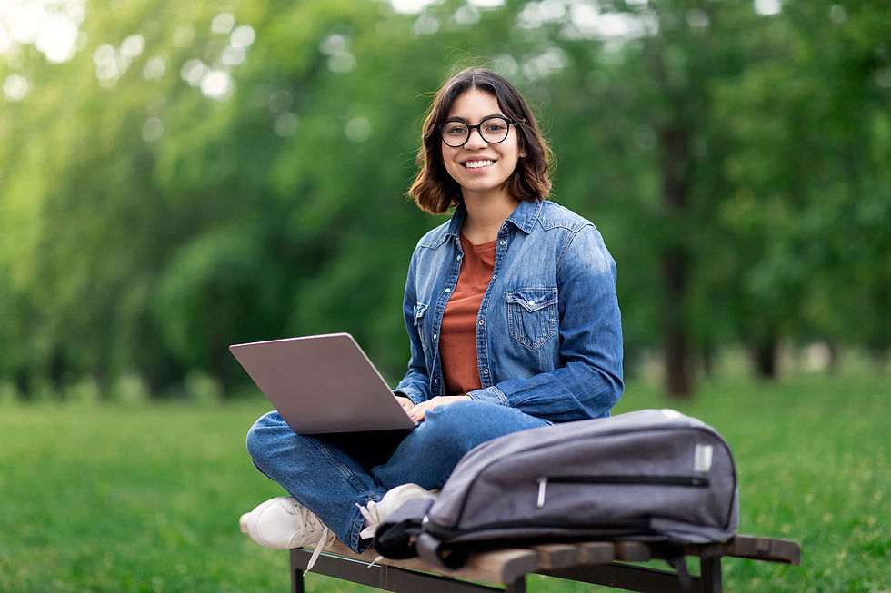Female student sitting in the grass with computer