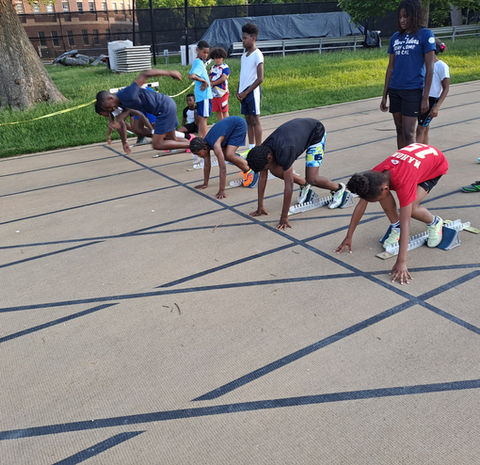 Young athletes in starting blocks on track preparing to race Youth Sports