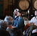 Two smiling people in an audience with wooden barrels