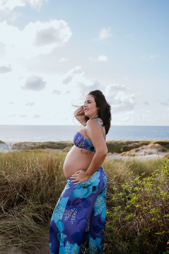 Mama-to-be embracing her beautiful baby bump in the stunning dunes of Kijkduin, radiating love and anticipation.