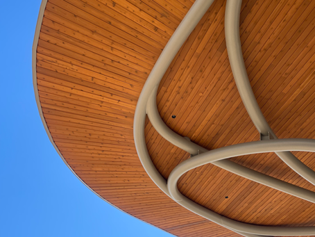 A wooden architectural detail with a steel column and blue sky