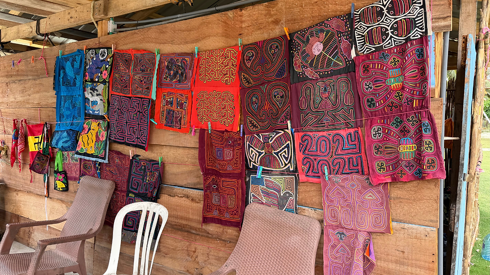 Colorful patterned Molas textile art hangs on a rustic wooden wall in a market stall in the San Blas Islands