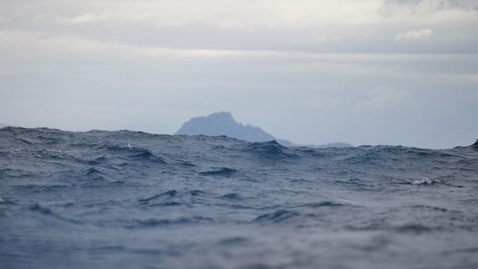 Wide shot of Southern Ocean waves with a distant island silhouette near Cape Horn