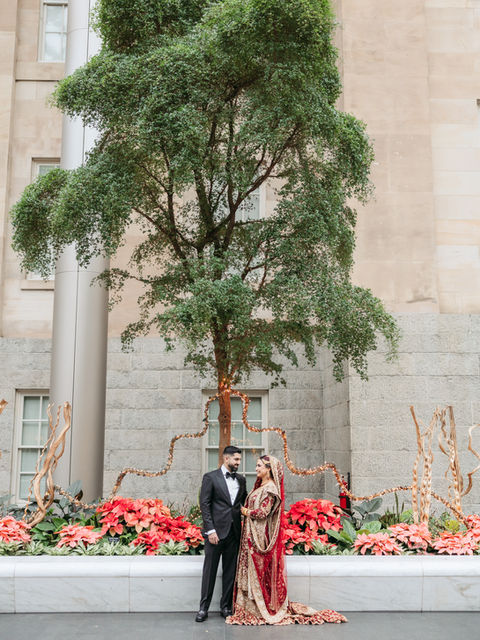 South Asian couple in wedding attire under a tree