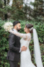 Bride and groom embracing, holding white bouquet