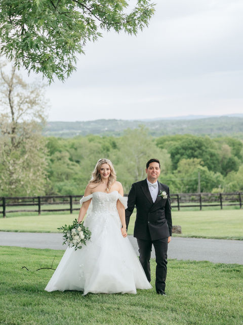 Bride in white wedding dress and groom holding hands outdoors