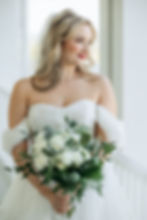 Bride in white dress holding a white rose bouquet