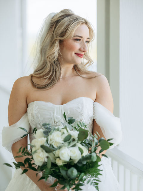 Smiling woman in a white strapless dress holding a bouquet