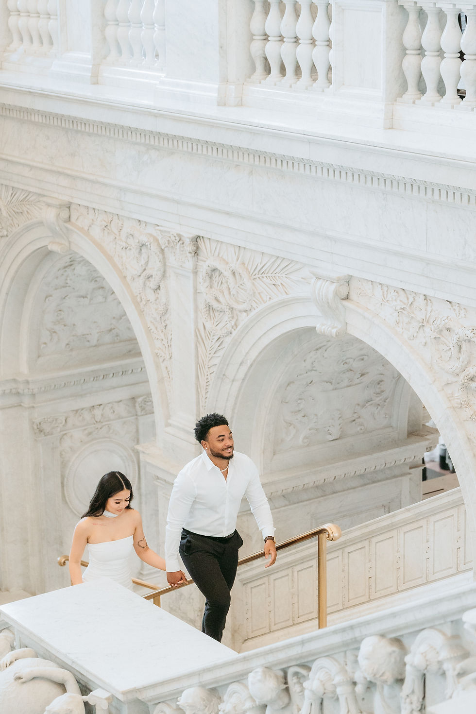 Happy couple walking up ornate white staircase