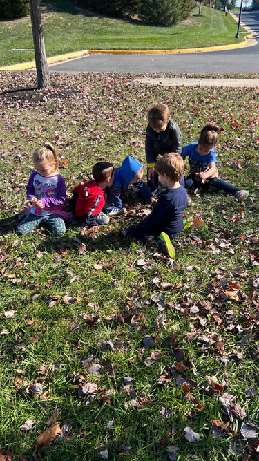 Kids having a picnic with their teacher outdoors