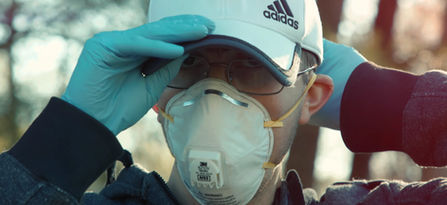 Person wearing N95 mask, glasses, and Adidas cap