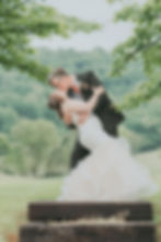 Wedding couple kissing, groom dips bride outdoors.