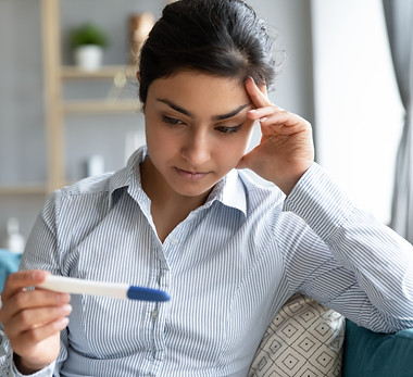 Worried young infertile indian woman holding pregnancy test negative result feel anxious s