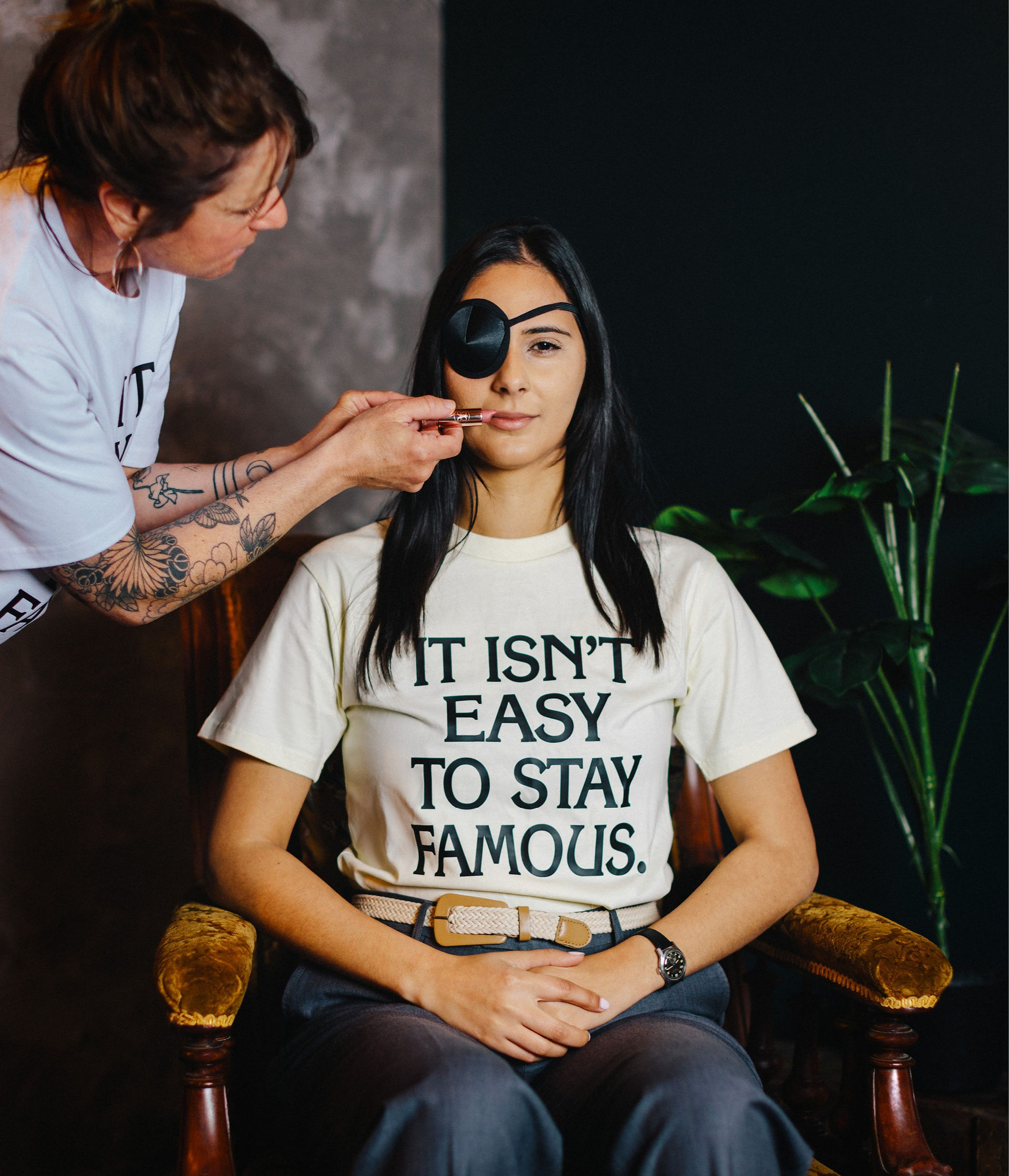 Woman wearing a white tee with a slogan, And wearing an eyepatch.