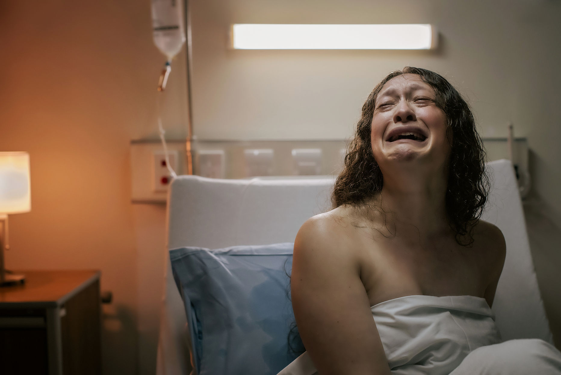 Anguished woman sitting upright in a hospital bed