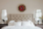 Pink wreath displayed on the wall above a bed