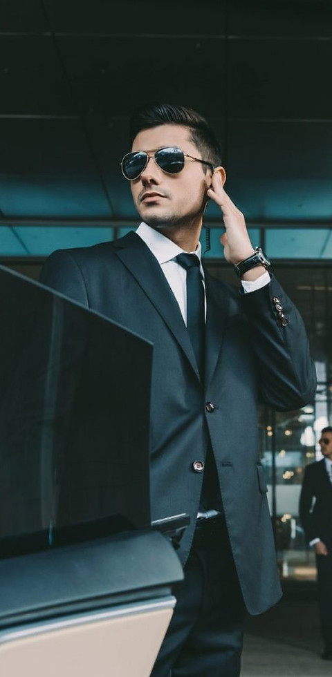 bodyguard-opening-car-door-for-businessman-and-listening-security-earpiece-e1631421593194-