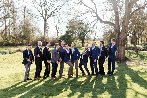 Groom and groomsmen grouphoto in front of trees in the sunshine