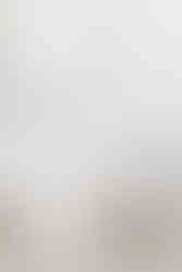 White couch in front of a white wall with a mac book, a book and a plate with a croissant on it