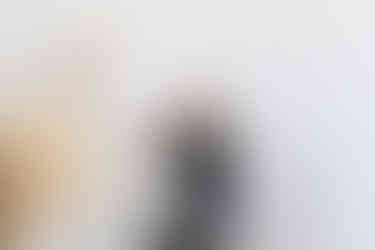 Blonde woman in black clothes sitting on a bar stool and smiling to someone she has on her phone