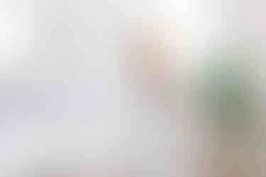 Blonde woman in a white room in thinking position, holding an ipad and wearing a headset