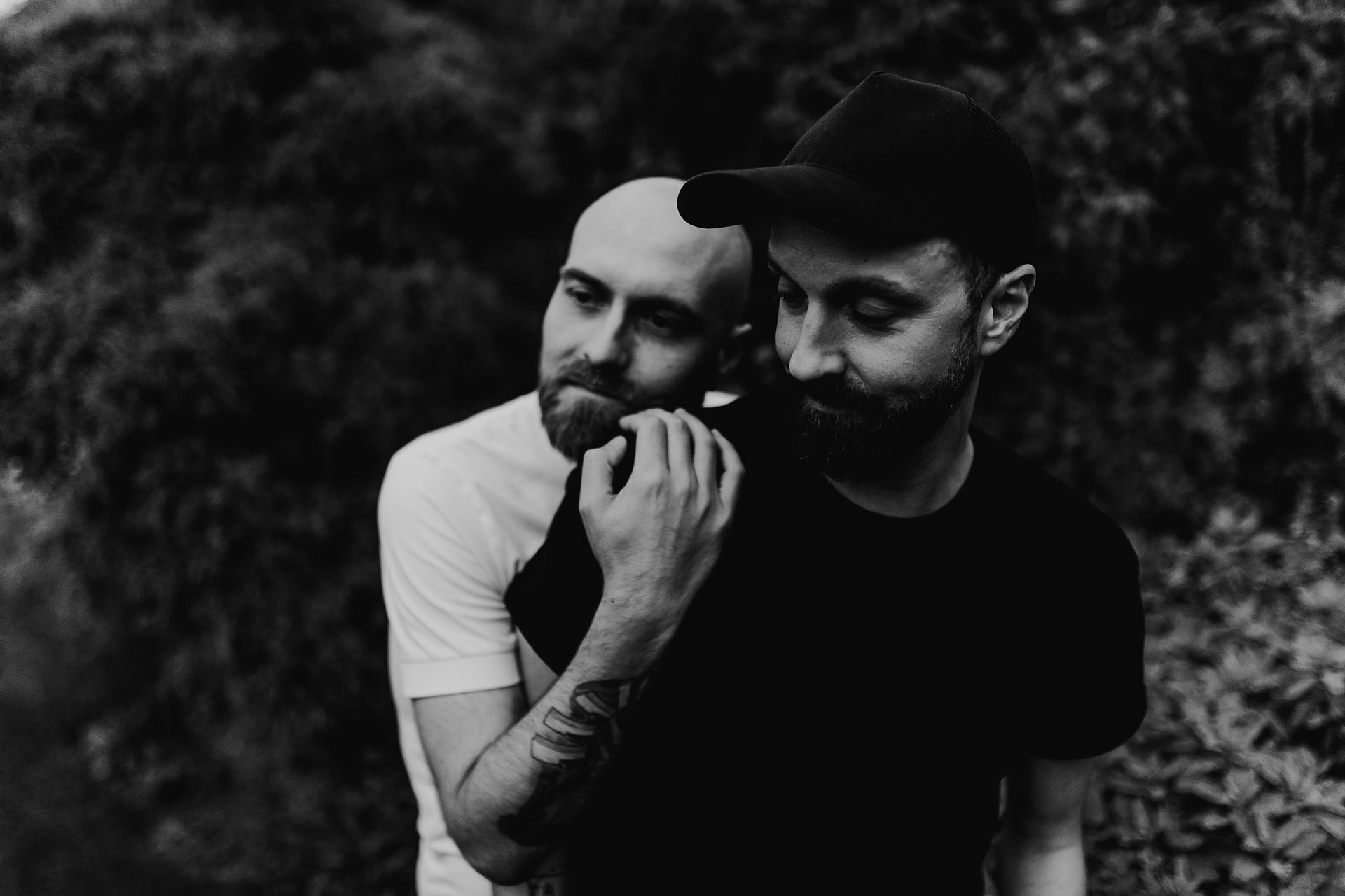 black and white photo of a gay couple, hugging from behind, little girl in the background