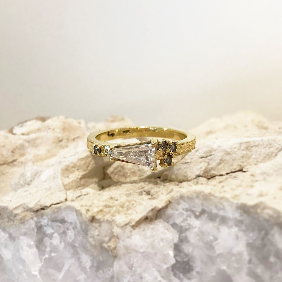 Thumbnail: Bespoke Tapered Diamond Baguette Engagement Ring with Sprinkle of Gray Diamonds and Modern Wheat Engraving in 18k