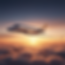 Sleek private jet flying over clouds at sunset
