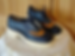 Chunky heeled oxford shoes with black and tan leather on a lace-covered table. Wooden door background adds a rustic feel.