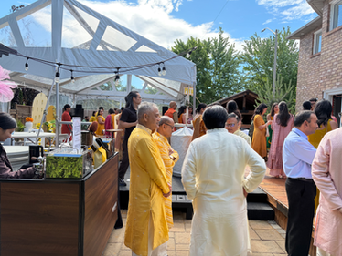 Guests in traditional attire at an outdoor event tent.