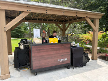 Outdoor mobile coffee bar under a wooden gazebo.